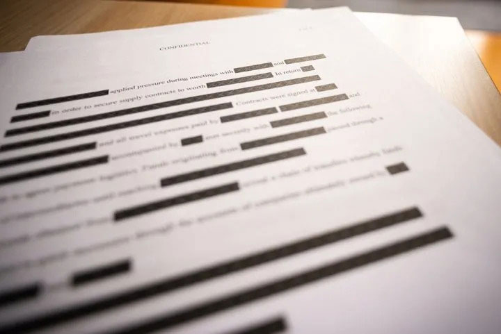 Confidential document with black redaction bars